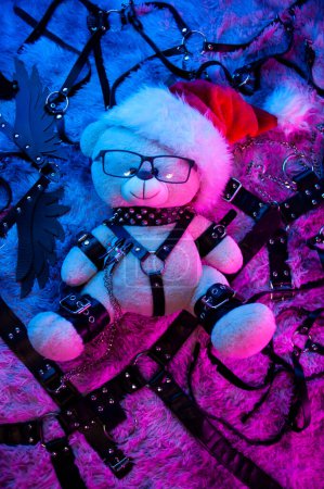 Photo for Bear in a Santa Claus hat is a Christmas gift for BDSM games from a sex shop in neon light for the new year - Royalty Free Image