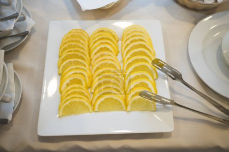 Téléchargez les photos : "Tranches de citron dans une assiette carrée sur la table à manger" - en image libre de droit