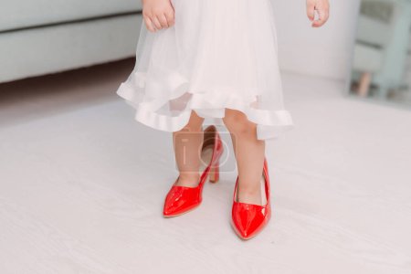 Téléchargez les photos : "Jambes de petite fille portant des talons hauts rouges" - en image libre de droit