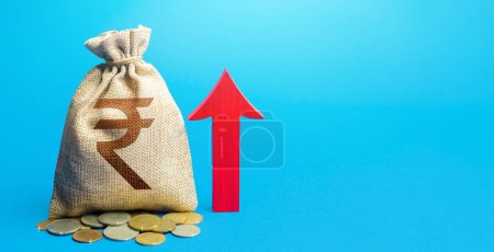 "Indian rupee money bag with red arrow up. Raising taxes. Deposit interest. Increase in profitability and prosperity, higher living standards. Recovery of financial system after crisis. Budget growth"