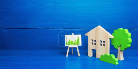 Photo for "Residential building and easel with green positive upward trend chart. Recovery of the real estate market, growing prices and demand for housing. Growth and development, investment. Energy efficiency" - Royalty Free Image