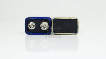 Foto de "Dos baterías PP3 usadas azules sobre un fondo blanco con reflexión. Batería principal para fuentes de alimentación personales. Primer plano de un conector de batería rayado y usado." - Imagen libre de derechos