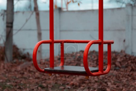 Photo for "Empty children's swing red color close-up. The concept of sadness, loss, death, mourning, orphanhood or loneliness." - Royalty Free Image
