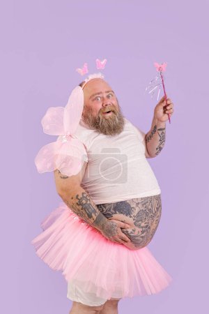 Téléchargez les photos : "Heureux plus la taille de la personne masculine en costume de fée pose sur fond violet" - en image libre de droit