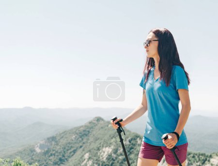 Photo for Active woman walking with trekking poles in summer mountains. - Royalty Free Image