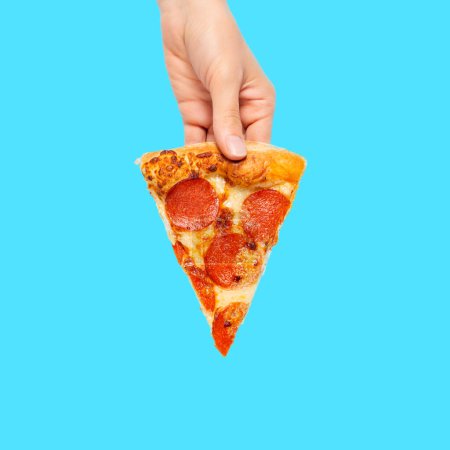 Photo for Slice of pepperoni pizza in hand isolated on blue. Top view on peperoni pizza. Concept for Italian food, street food, fast food, quick bite. - Royalty Free Image