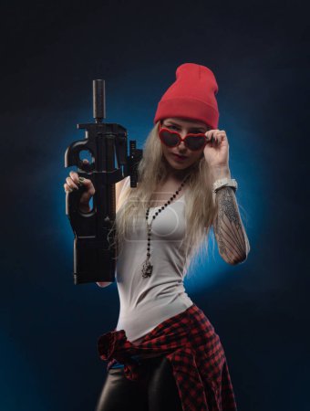 a bright blonde in a red hat with a submachine gun on a dark background