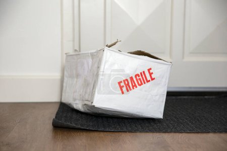 Téléchargez les photos : Battre boîte de livraison endommagée avec autocollant fragile, emballage en carton livré cassé à la maison - en image libre de droit