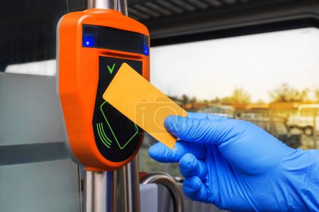 Photo for Man's hand in a protective medical glove applies a card to an automatic toll terminal in a modern electric train, close-up - Royalty Free Image
