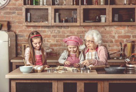 Téléchargez les photos : "Petites filles aident mamie à faire des biscuits
" - en image libre de droit
