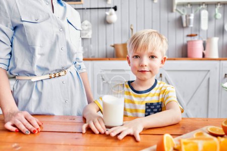 Foto de "Comida saludable, fruta fresca, naranjas jugosas. El chico sonríe mientras desayuna en la cocina. Mañana brillante en la cocina." - Imagen libre de derechos
