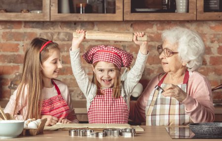 Téléchargez les photos : Heureux grand-mère et petites-filles cuisine - en image libre de droit