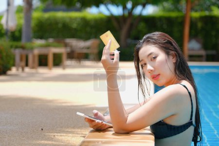 Photo for Online payment, A teenage girl who swims is using her credit card with her phone to make purchases. online via internet - Royalty Free Image