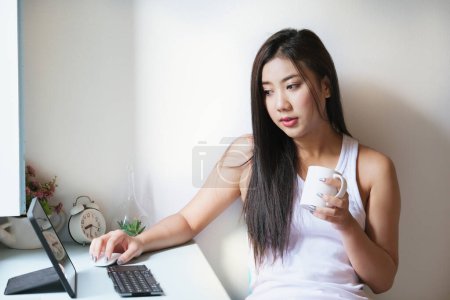 Téléchargez les photos : New normal, a businesswoman using tablet to work for a company Via the internet on your desk at home - en image libre de droit