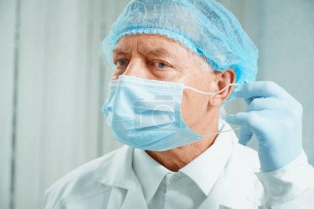 Téléchargez les photos : Un chirurgien plus âgé enlève son masque - en image libre de droit