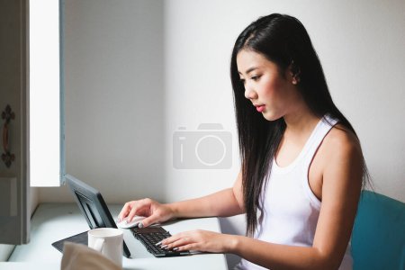 Foto de "nueva era normal, Una empleada de la empresa utiliza una tableta para trabajar desde casa debido a la situación coronavirus.." - Imagen libre de derechos