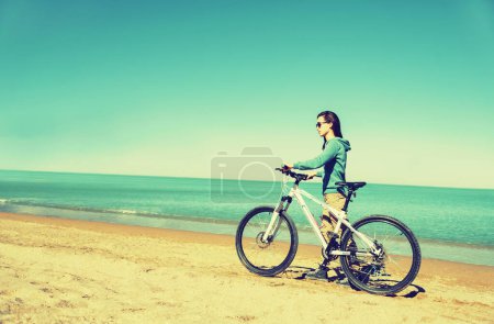Foto de Chica caminando con una bicicleta en la playa - Imagen libre de derechos