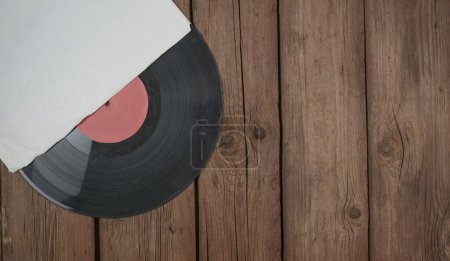 Photo for Old vinyl record in paper case on wooden rustic background. - Royalty Free Image
