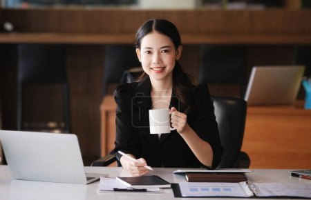 Foto de Mujer sentada en el trabajo usando computadora, tableta y documentos en su trabajo. - Imagen libre de derechos