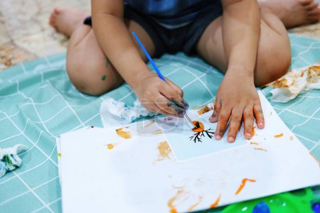 Photo for Focus on hands on paper. Children use paintbrushes to paint watercolors on paper to create their imagination and enhance their learning skills. - Royalty Free Image