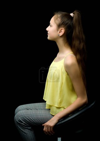 Foto de Una adolescente está sentada en una silla de cuero
. - Imagen libre de derechos
