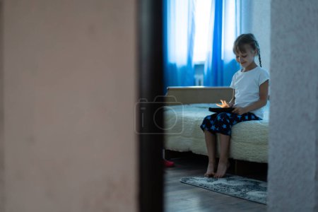 Téléchargez les photos : Jeune enfant mignon utilisant une tablette numérique dans un intérieur de la maison - en image libre de droit