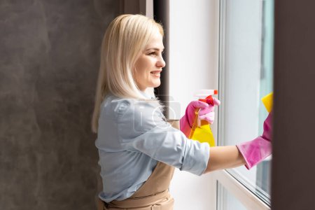 Téléchargez les photos : "La femme lave une fenêtre dans l'appartement" - en image libre de droit