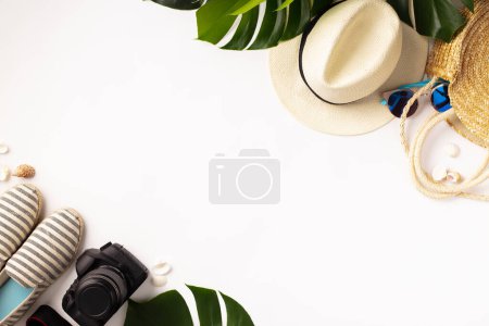 Foto de Sombrero de paja, cámara, bolso, zapatos de verano, gafas de sol, conchas y hojas tropicales sobre fondo blanco, vista superior. - Imagen libre de derechos