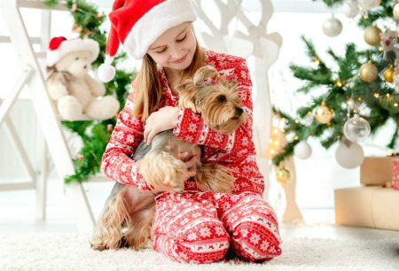 Téléchargez les photos : Enfant en période de Noël, mignonne petite fille jouant avec le chien - en image libre de droit
