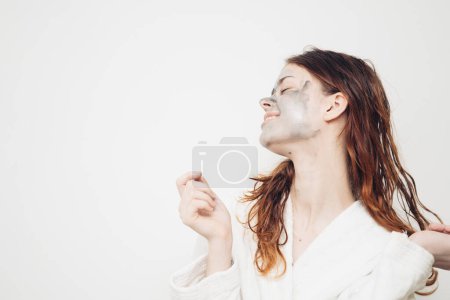 Téléchargez les photos : Femme gaie en peignoir soin de la peau crème visage - en image libre de droit