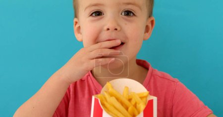 Photo for Young boy indoors eating fish and chips smiling - Royalty Free Image
