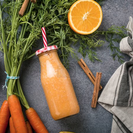 Photo for Healthy carrot smoothie with orange and cinnamon in glass bottle - Royalty Free Image