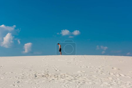 Photo for Young sporty man want doing acrobatic exercises on the sand near river - Royalty Free Image
