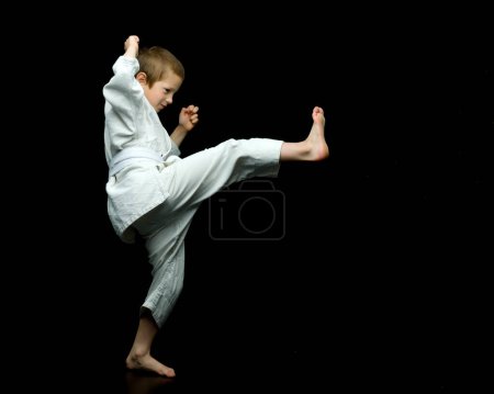 Foto de Un niño pequeño en un kimono blanco cumple golpes - Imagen libre de derechos