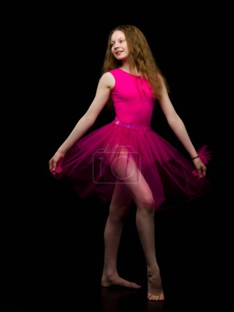 Photo for Girl gymnast in the studio on a black background performs gymnastics - Royalty Free Image