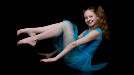 Téléchargez les photos : Fille gymnaste dans le studio sur un fond noir - en image libre de droit