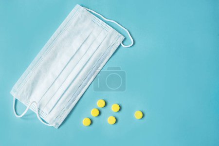 Photo for Respiratory mask and medicine in capsules on blue background. - Royalty Free Image