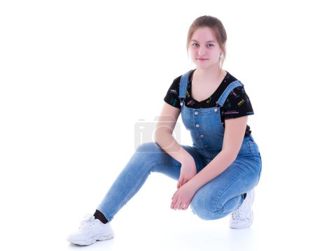 Téléchargez les photos : Adolescente posant par terre dans le studio. Le concept de style et de mode. - en image libre de droit