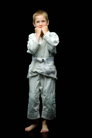 Foto de Un niño pequeño en un kimono blanco cumple golpes - Imagen libre de derechos