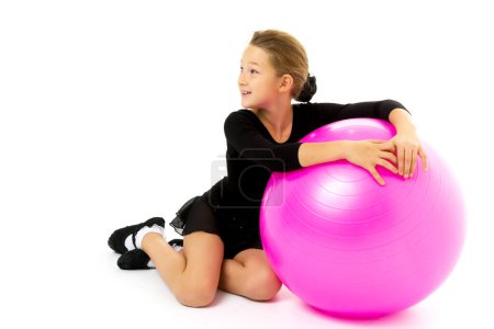 Téléchargez les photos : Petite fille faire des exercices sur une grosse balle pour la forme physique. - en image libre de droit