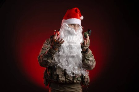 Téléchargez les photos : Un homme en uniforme militaire avec une arme et un chapeau du Père Noël - en image libre de droit