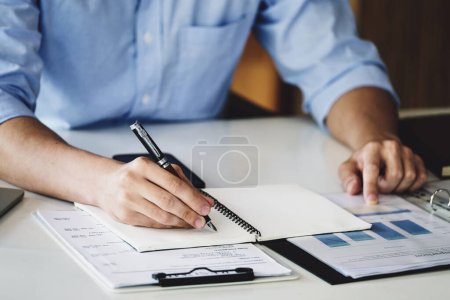 Photo for Financial budget audit A male auditor is using a pen to write down budgets to trace the company's financial fraud. - Royalty Free Image