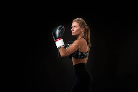 Téléchargez les photos : Belle athlète féminine en gants de boxe, en studio sur fond noir - en image libre de droit