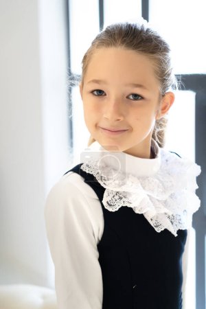 Photo for Beautiful little schoolgirl girl posing in studio near a large window. - Royalty Free Image