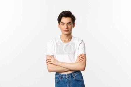 Photo for "Image of sassy gay man in crop top smiling, looking confident, cross arms on chest and standing over white background" - Royalty Free Image