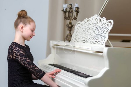 Téléchargez les photos : "La fille est au piano à queue blanc." - en image libre de droit