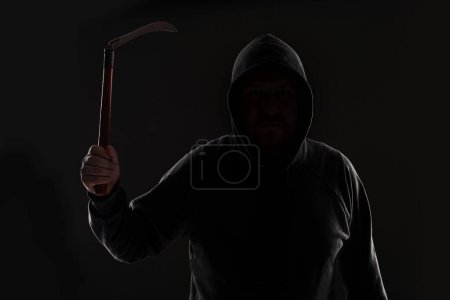 Photo for "Criminal in dark clothes and balaclava with scythe" - Royalty Free Image