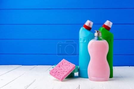 Foto de Detergente limpiador y esponjas sobre la mesa sobre fondo azul - Imagen libre de derechos