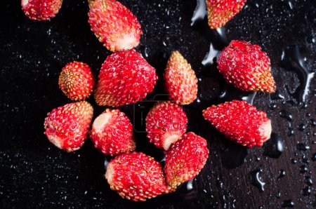 Photo for Bright red wild strawberries on a black background in the water - Royalty Free Image