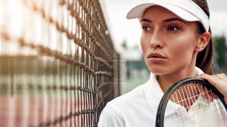 Téléchargez les photos : Rien n'est impossible. Portrait de jeune belle joueuse de tennis avec une raquette sur un court, regardant ailleurs
. - en image libre de droit